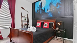 A bedroom with a large bed, a wall-mounted projector displaying a castle scene, a wooden ladder, and a small shelf with decorative items. - Family Disney Paradise with Pool & Game Room  (Davenport)