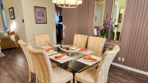 A dining area with a glass table, six beige upholstered chairs, and a chandelier. - Family Disney Paradise with Pool & Game Room  (Davenport)