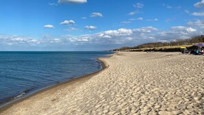 Une plage de sable fin, sous un ciel bleu azur parsemé de quelques nuages.
