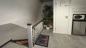 Ein Flur mit Treppe, einem Blumentopf, einer Tür mit Schild und einer Mikrowelle.