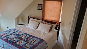 A bedroom with a bed, a nightstand, a lamp, a window with blinds, and a door. - 3 bedroom, 2.5 bath unit - Ocean, bay and pool all in a day! (Lewes)