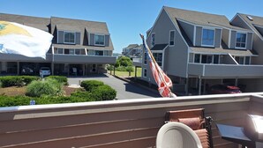 A residential area with houses, a flag, and a patio with outdoor furniture. - 3 bedroom, 2.5 bath unit - Ocean, bay and pool all in a day! (Lewes)