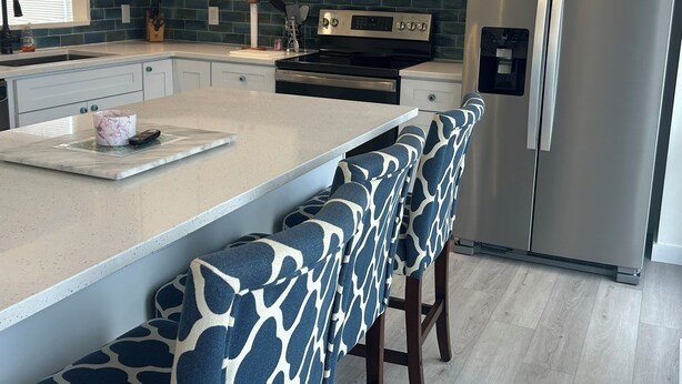 A modern kitchen with a central island, stainless steel appliances, and patterned bar stools. - 3 bedroom, 2.5 bath unit - Ocean, bay and pool all in a day! (Lewes)