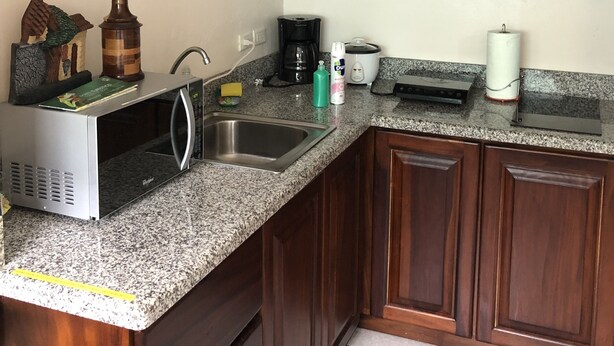 Una cocina con armarios de madera, microondas, cafetera y tostadora.