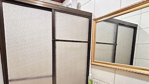 Un baño con lavamanos blanco, inodoro, espejo con marco dorado y zona de ducha con puertas de vidrio esmerilado.