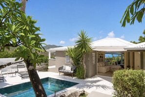 A poolside area with a lounge chair, a small table, and a potted plant. - Villa Cazou, vue mer, piscine privée, Wifi 100Mbps (Oyster Pond)
