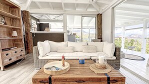 A spacious living area with a large white sofa, a wooden coffee table, and a view of the outdoors. - Villa Cazou, vue mer, piscine privée, Wifi 100Mbps (Oyster Pond)