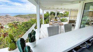A covered outdoor seating area with a view of the beach and hills. - Villa Cazou, vue mer, piscine privée, Wifi 100Mbps (Oyster Pond)