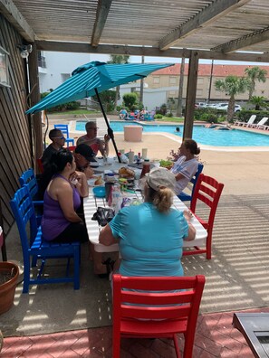 Enjoy al fresco dining in a serene outdoor setting with a pool and lounge chairs nearby.