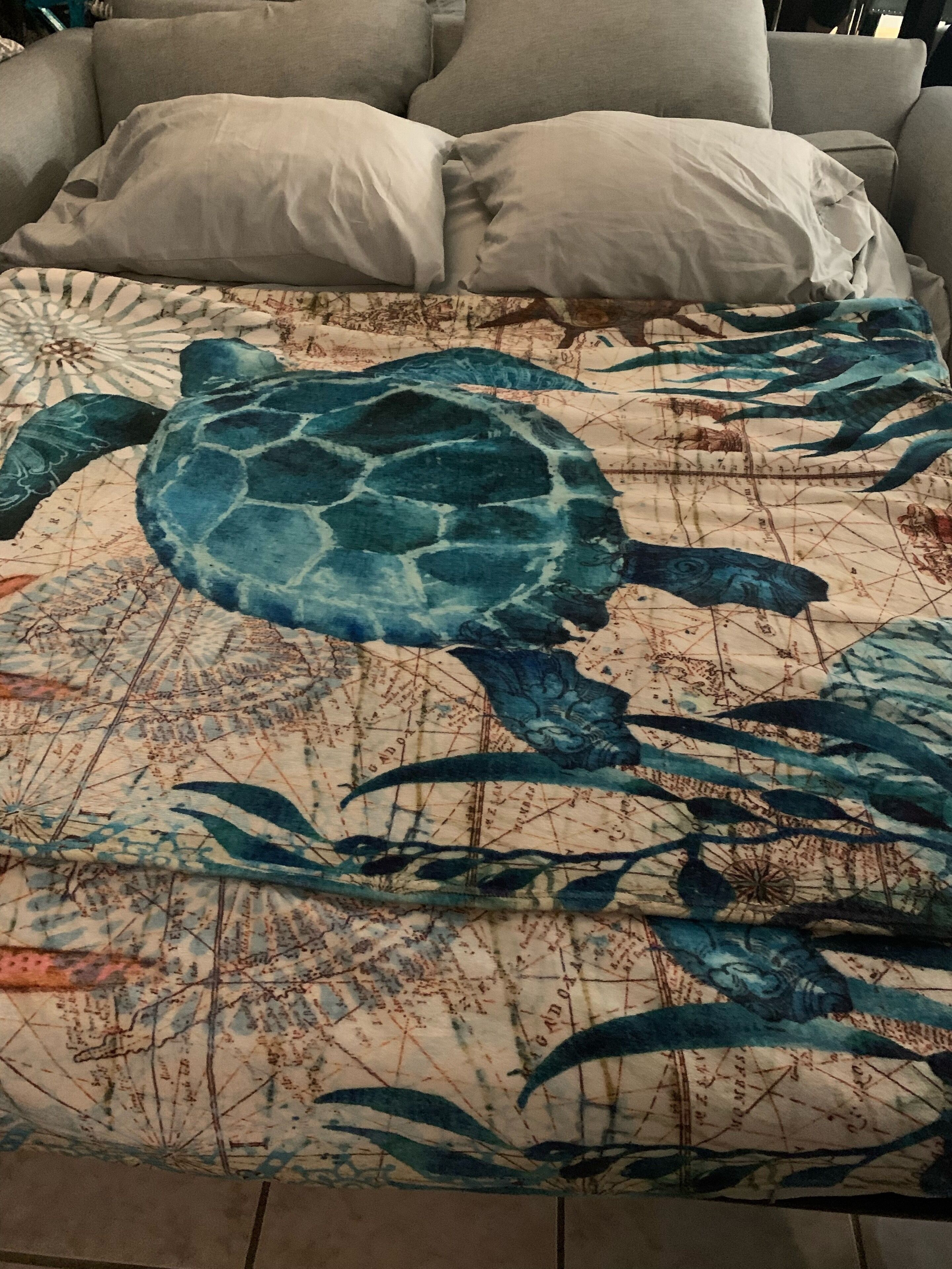 Un lit avec une grande et détaillée représentation d’une tortue de mer sur la couvre-lit.