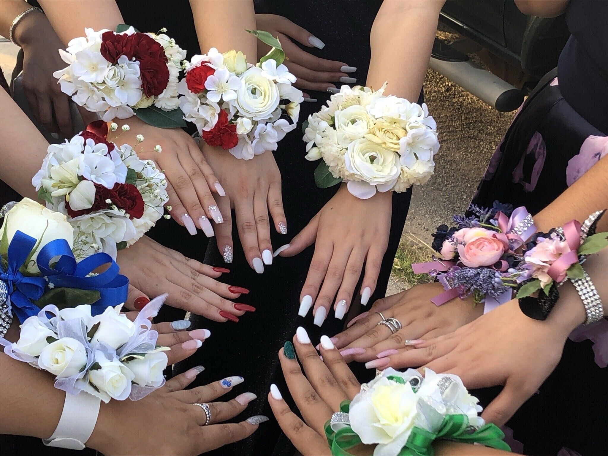 A group of hands with wedding bouquets and rings.