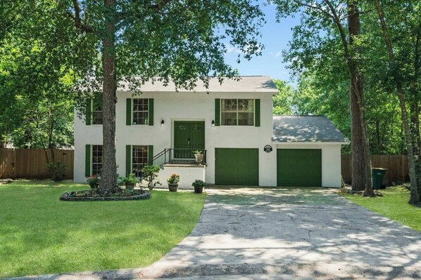 A two-story house with a front porch, green shutters, and a garage.
