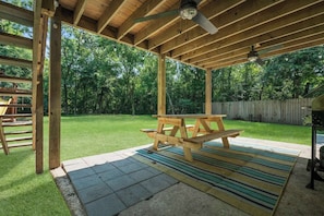 Enjoy al fresco dining on the patio, surrounded by a beautifully maintained lawn and a wooden fence.
