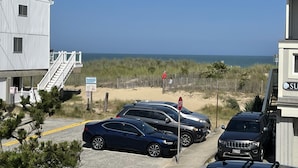 Een pand aan het strand met een parkeerplaats, een trap naar een gebouw en uitzicht op de oceaan.