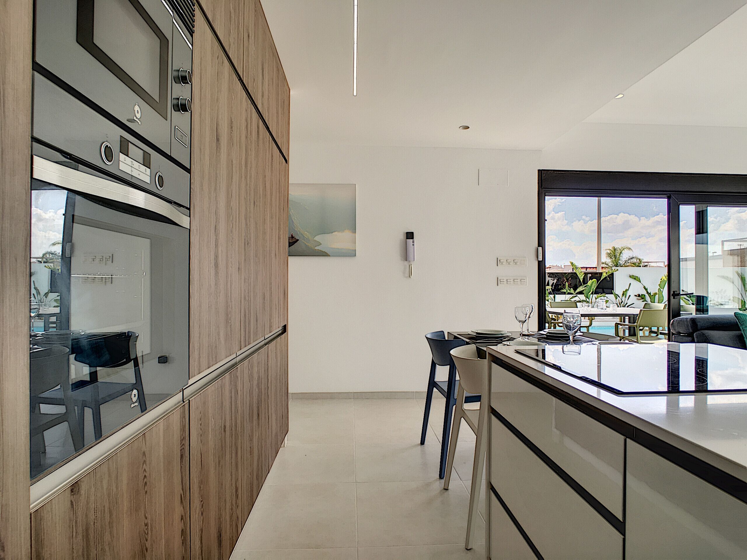 Une cuisine moderne avec des meubles en bois, un grand îlot central et une vue sur l’extérieur.