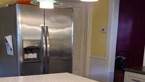 Una cocina con refrigerador de acero inoxidable, encimera de granito e iluminación colgante.