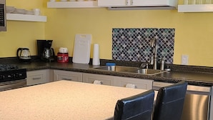 Una cocina moderna con una isla central, dos lámparas colgantes, armarios blancos y salpicadero de azulejos.