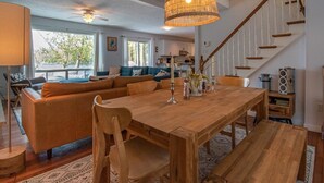 Un salón espacioso con una mesa de comedor de madera, un sofá grande y una escalera.