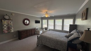 A bedroom with a bed, dresser, two chairs, a ceiling fan, and a TV. - Lake Murray Lake Front Home W/Kayaks , close to Dreher Island (Prosperity)