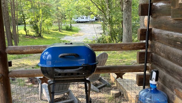 A wooden porch with a grill and a water dispenser. - Rustic Bee Cabin - camping (Hardin)