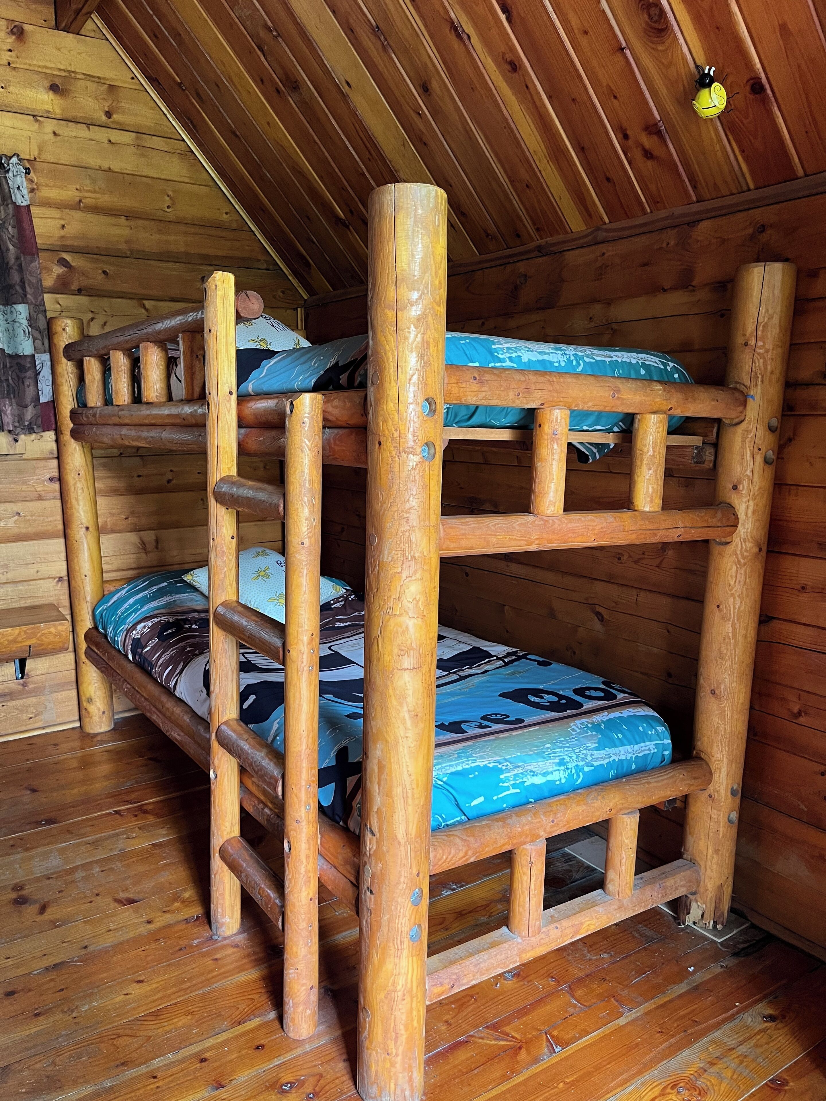 Un lit superposé avec une échelle en bois et un matelas bleu.