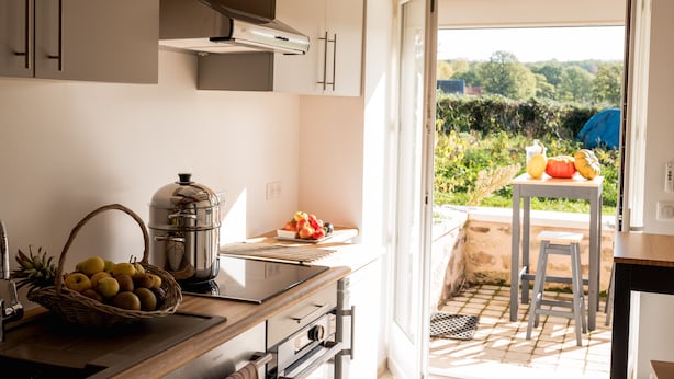 Una cocina con cafetera, cesta de fruta y vistas al jardín.