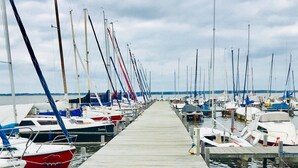 Een houten steiger die uitkomt bij een jachthaven met boten aan beide kanten.