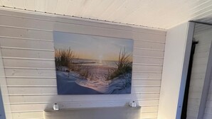 Een slaapkamer met een bed, kussens, een dekbed, een schilderij en nachtlampjes.