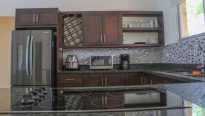 A modern kitchen with dark wooden cabinets, stainless steel appliances, and a tiled backsplash.