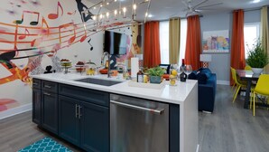 A modern kitchen with a central island, stainless steel appliances, and a colorful wall mural. - The Six1five by Extremely Suite★4 beds/4baths★9 BEDS★ROOFTOPDECK★HUGE SPACE (Nashville)