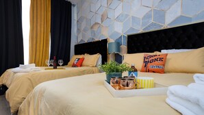 A hotel room with two beds, each with a headboard, a bedside table with a lamp, a tray with a plant, wine glasses, and a pillow with a logo. - The Six1five by Extremely Suite★4 beds/4baths★9 BEDS★ROOFTOPDECK★HUGE SPACE (Nashville)