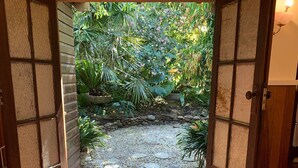 Eine Holztür, die in einen Garten mit Kiesweg und trittsteinen führt.