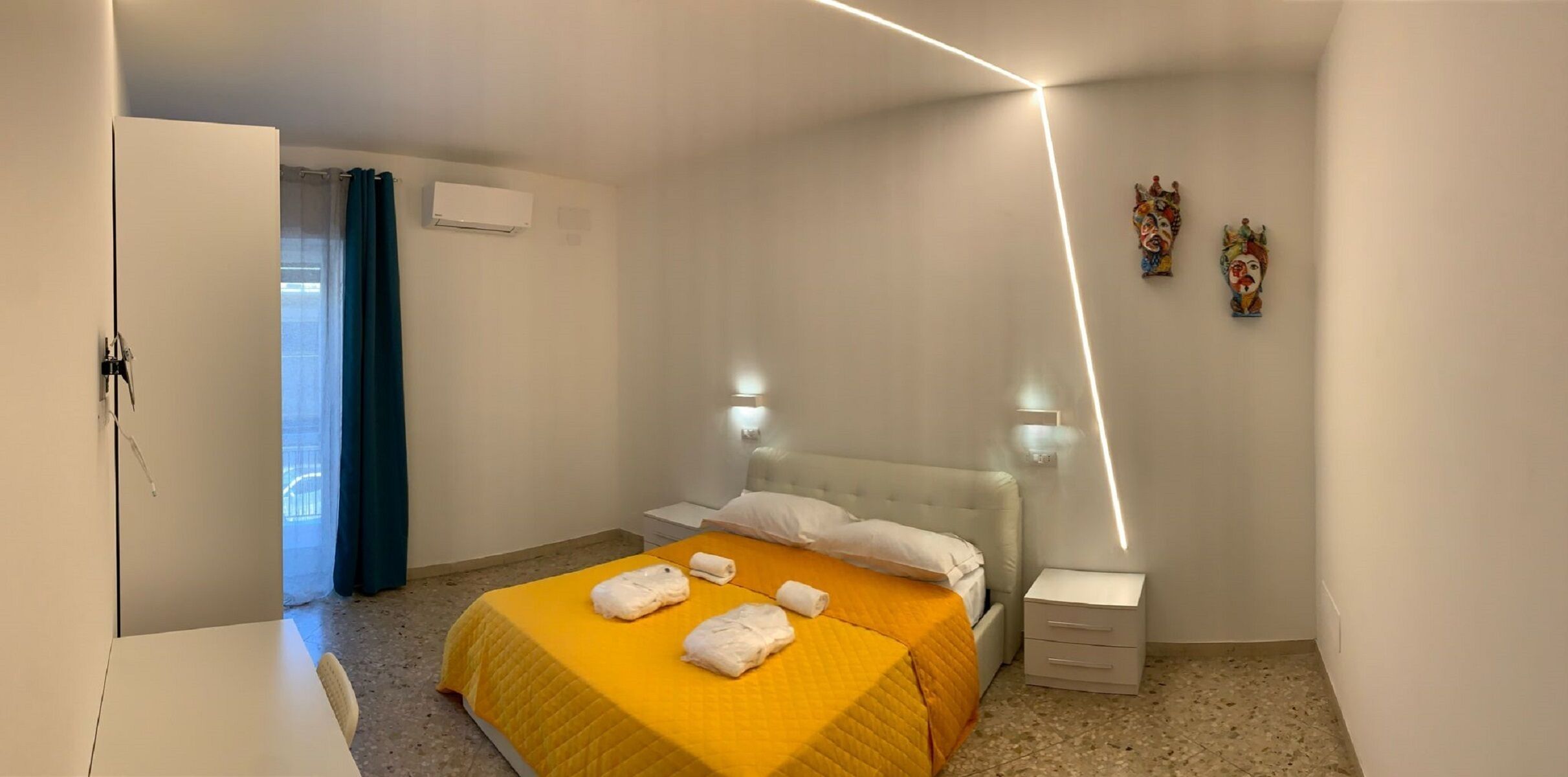 A hotel room with a bed, bedside tables, a wardrobe, and a bathroom visible through a door.