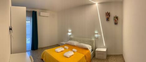 A hotel room with a bed, bedside tables, a wardrobe, and a bathroom visible through a door.
