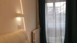 Een moderne kamer met een bank, een klein tafeltje, een radiator en een raam met gordijnen.