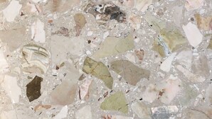 Een detailopname van een terrazzovloer met stenen in verschillende vormen en kleuren.