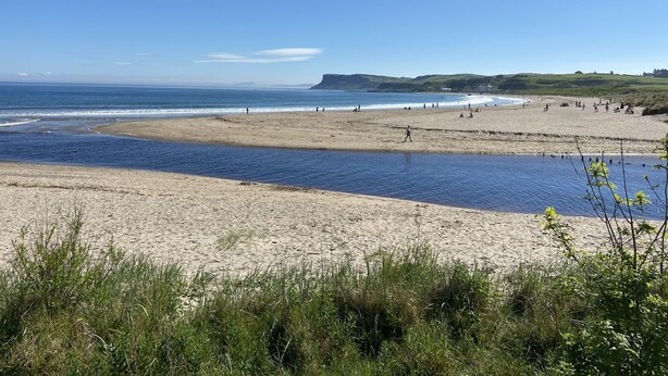 Een strand met heldere lucht en rustig water.