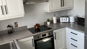 Een moderne keuken met witte kastjes, een inbouwoven, een koffiezetapparaat en een broodrooster.