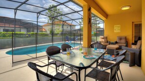 En inglasad uteplats med pool, utemöbler och fri utsikt över det omgivande bostadsområdet.