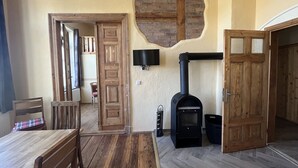 A cozy room with a wooden table, chairs, a fireplace, and a TV mounted on the wall. - Bernsteinwohnung Gutshaus Reidervitz (Altenkirchen)