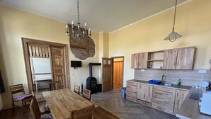 A spacious kitchen with wooden cabinets, a dining area with a wooden table and chairs, and a built-in stove. - Bernsteinwohnung Gutshaus Reidervitz (Altenkirchen)