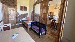 A cozy room with a bed, wooden furniture, a dining table, and a kitchen area visible through an open door. - Bernsteinwohnung Gutshaus Reidervitz (Altenkirchen)
