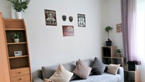 Ein Wohnzimmer mit grauem Sofa, Holzregalen und Wanddekorationen, darunter Schilder und eine Pflanze.