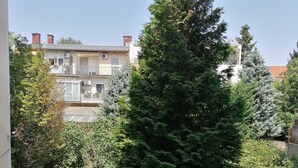 Ein Wohngebiet mit einer großen Nadelbaum, einem Pfad und einem Gebäude mit Balkonen und Klimaanlagen.