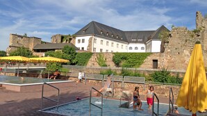 Zona piscina con parete in pietra e un grande edificio sullo sfondo.