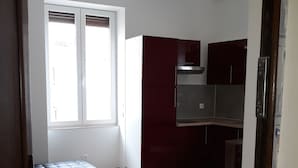 Eine moderne Küche mit dunkelroten Schränken, einer Edelstahl-Dunstabzugshaube und einem hellen Holzboden.