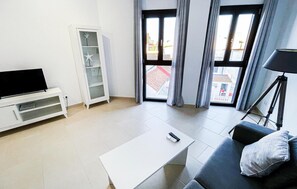 Relax in this stylish living room with a flat-screen TV, grey sofa, and white coffee table.