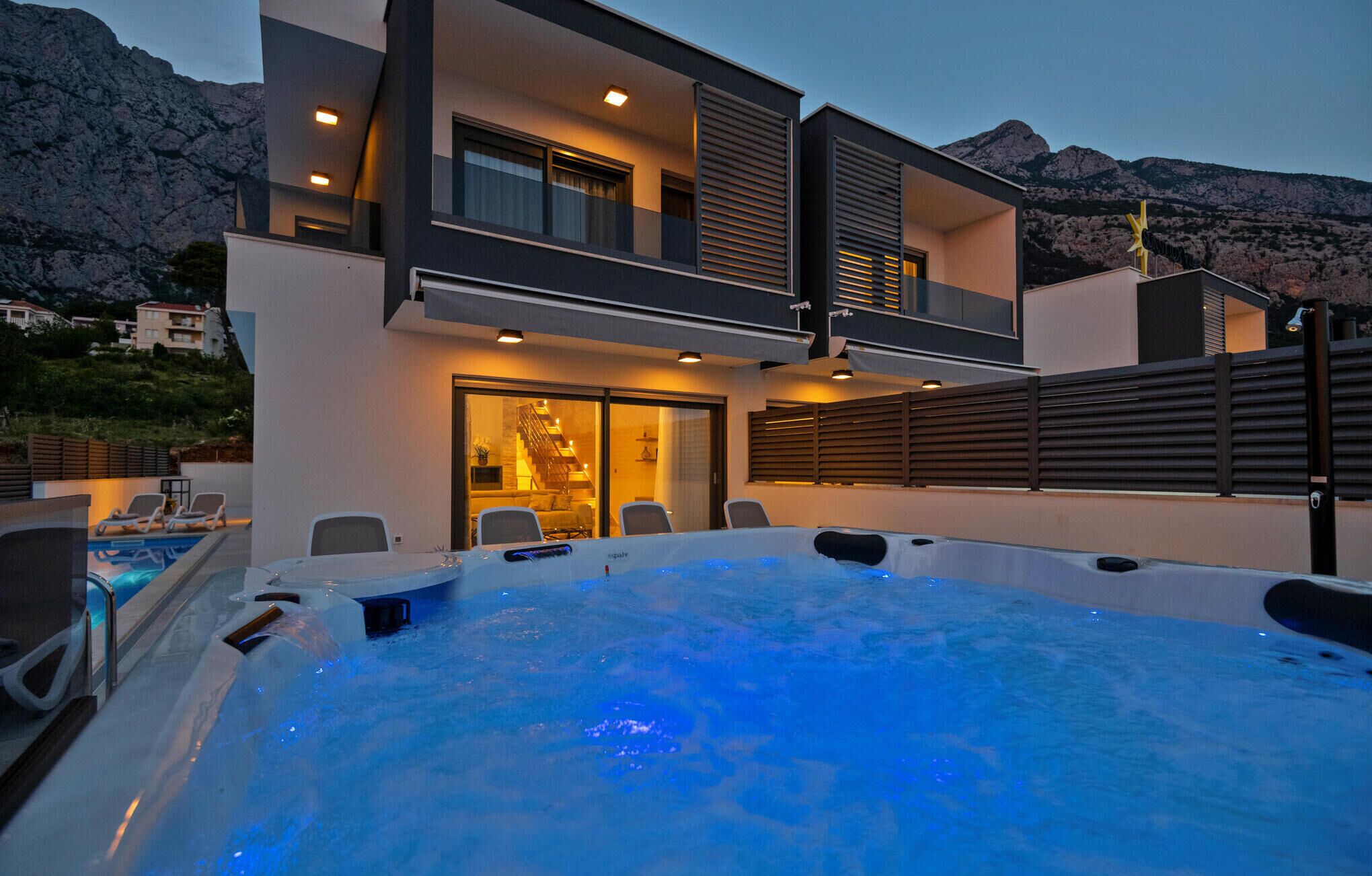 A modern two-story building with a hot tub and outdoor seating area.