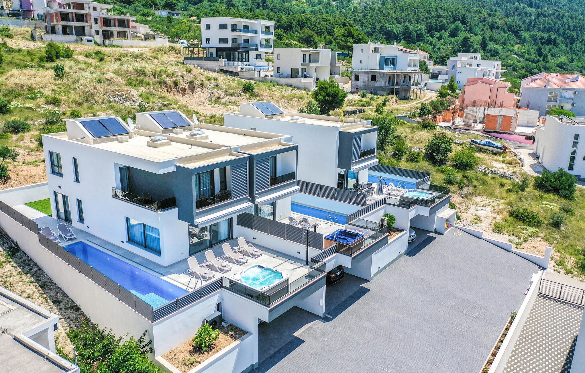 Una casa moderna de dos pisos con piscina en la azotea, jacuzzi y paneles solares.