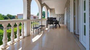 A covered balcony with a white balustrade, a stone wall, and a view of the surrounding area. - Nice apartment in Labin with swimming pool (Labin)